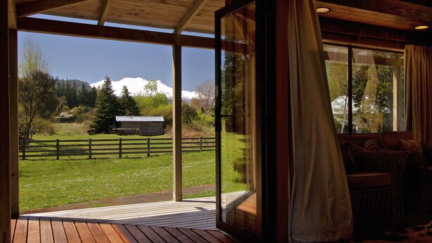 Une terrasse en bois offrant une vue sur une montagne et un champ clôturé.