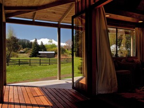 A wooden deck with a view of a mountain and a fenced field. - Ti Kouka Chalet - Ohakune Holiday Home (Ohakune)