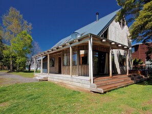 A wooden house with a covered porch and a chimney. - Ti Kouka Chalet - Ohakune Holiday Home (Ohakune)