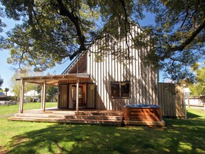 Una casa de madera con porche cubierto y jacuzzi.