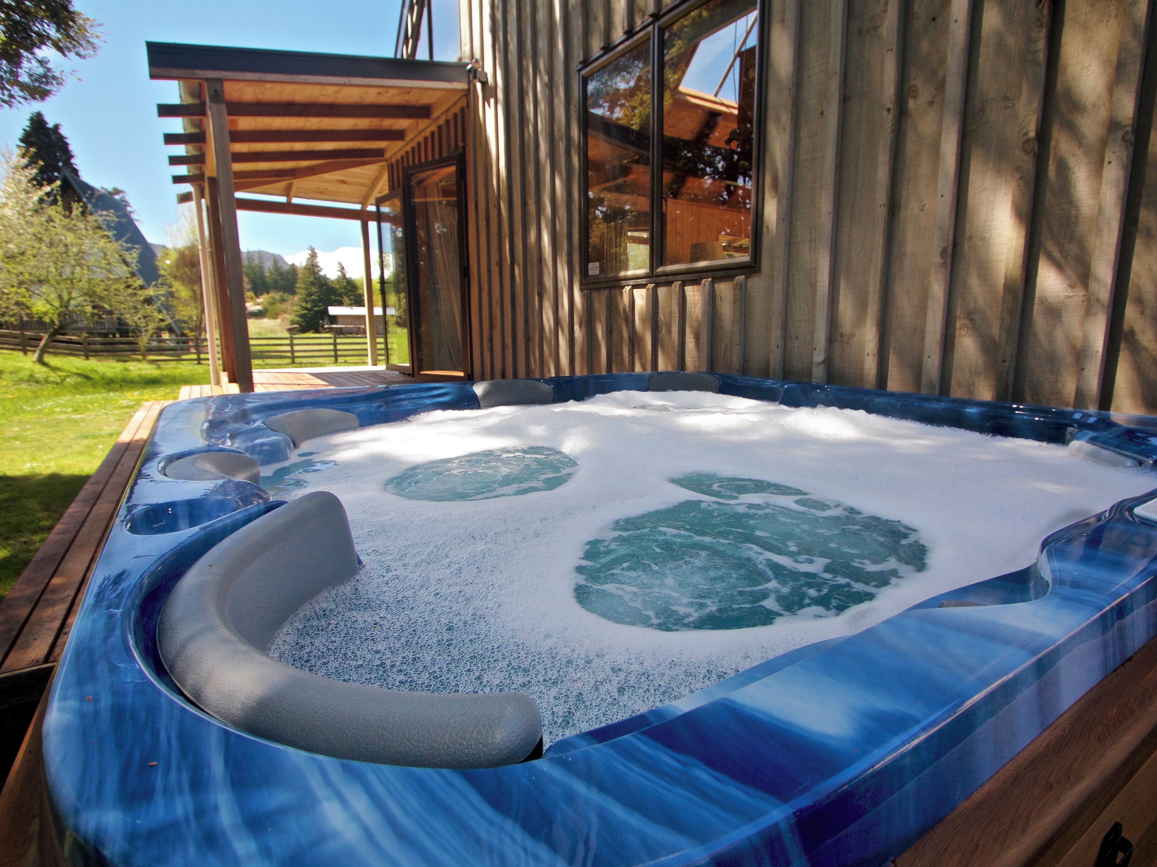 Uma banheira de hidromassagem com um deck de madeira e uma casa ao fundo.