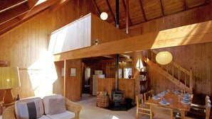 L'intérieur d'un chalet en bois chaleureux et accueillant, avec un canapé, une table à manger et une cheminée.