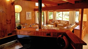 L’intérieur d’un chalet en bois comprend un coin repas, une cheminée et un espace salon confortable avec vue sur l’extérieur.