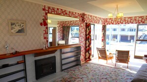 Une pièce avec une cheminée, un miroir, une moquette à motifs floraux, un lit et une vue sur l’extérieur.