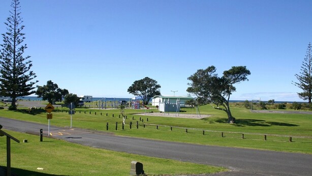 A road with a speed limit sign, grassy areas, and a small building.