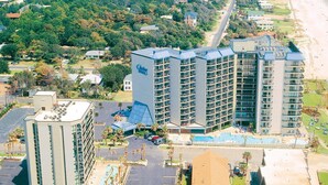 Un hotel de gran altura con varios balcones, piscina y vistas a la playa.