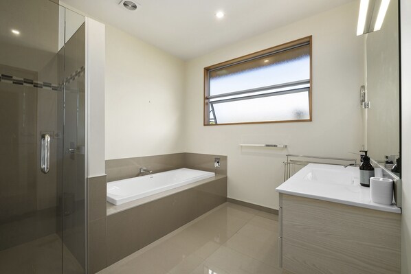 A modern bathroom with a glass-enclosed shower, a large bathtub, and a vanity with a mirror. - Infinity Views - Modern Wanaka Holiday Home (Wanaka)