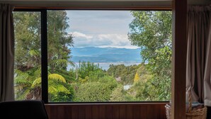 Een kamer met een groot raam dat uitzicht biedt op een weelderig landschap met bomen en bergen.