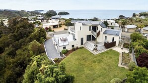 A modern two-story house with a large front yard and a view of the sea. - Sun, Sea, Sensational - Kaiteriteri Holiday Home (Kaiteriteri)