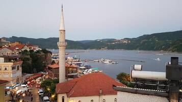 A coastal town with a prominent minaret, a marina with boats, and a bustling street with pedestrians and vehicles.