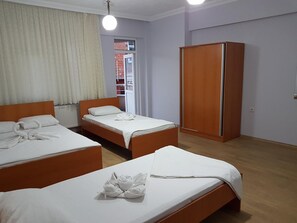 Une chambre d’hôtel avec deux lits simples, une armoire et une fenêtre avec des rideaux.
