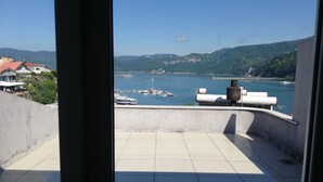A balcony with a view of a harbor, boats, and a distant town. - Karadeniz Pansiyon (Amasra)