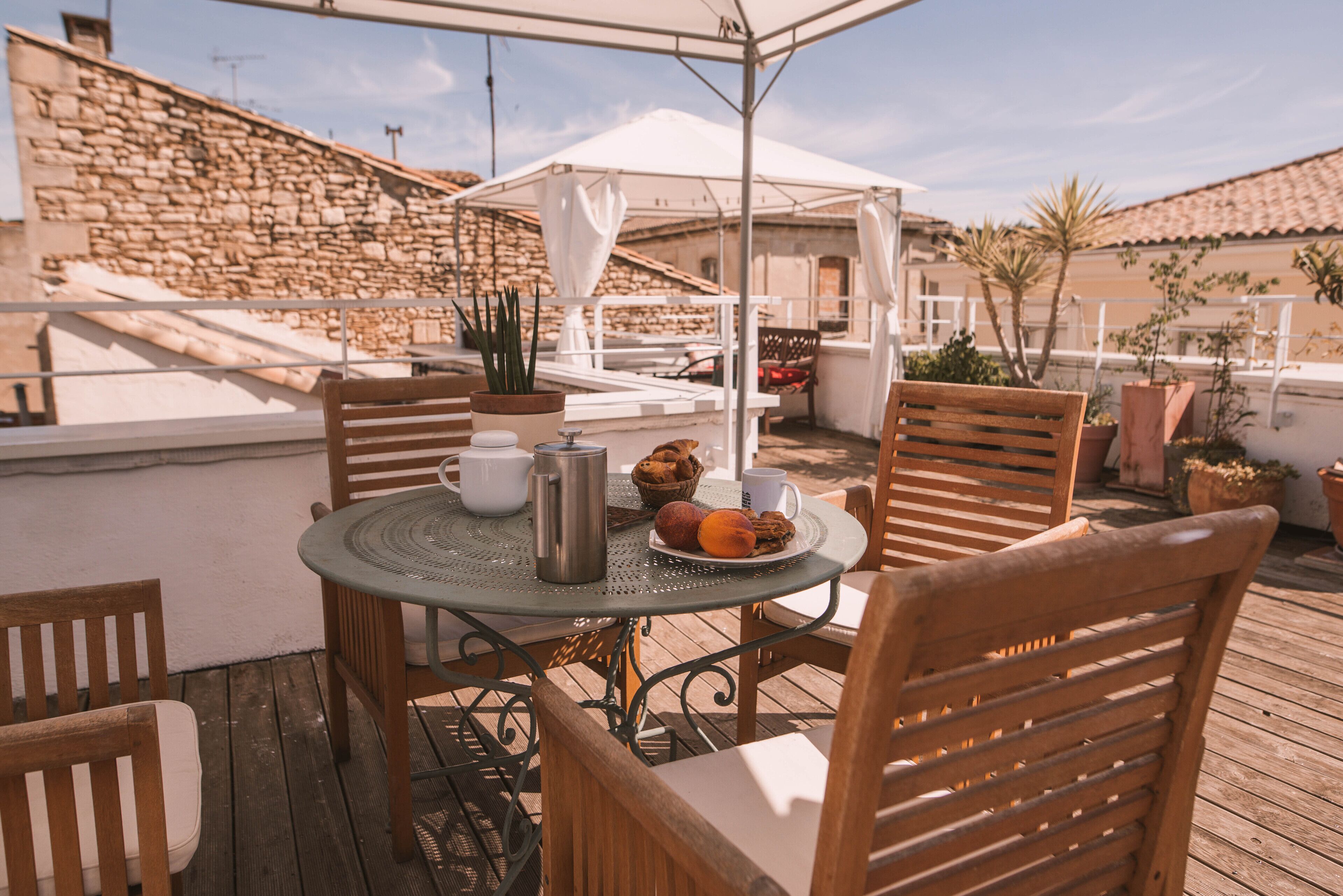 A wooden deck with a round table, chairs, and a white umbrella.