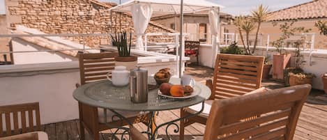 A wooden deck with a round table, chairs, and a white umbrella.