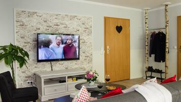 Ein Wohnzimmer mit Fernseher, Sofa, Couchtisch und einer Garderobe.