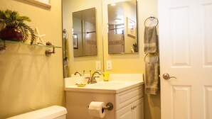 A bathroom with a toilet, sink, mirror, and towel rack. - Nani Kai Hale #304 on Sugar Beach (Kihei)