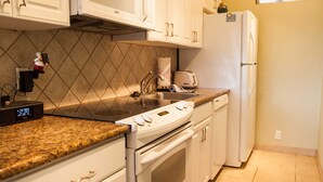 A kitchen with white cabinets, a microwave, a stove, a refrigerator, and a sink. - Nani Kai Hale #304 on Sugar Beach (Kihei)