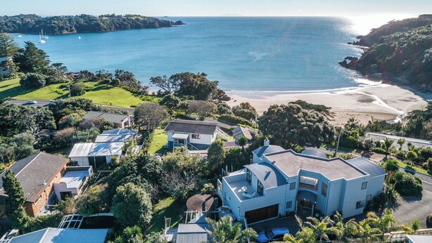 An aerial view of a coastal residential area with houses, a beach, and boats in the water.