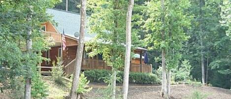 A cabin with a porch, surrounded by trees.