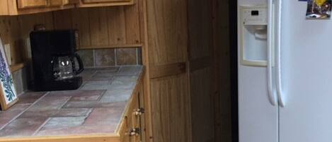 A kitchen with wooden cabinets, a coffee maker, and a white refrigerator with magnets and papers.