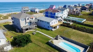 Ett bostadsområde med hus, en swimmingpool och en strand i bakgrunden.