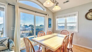 A dining area with a table and chairs, a view through a glass door, and a clock on the wall.