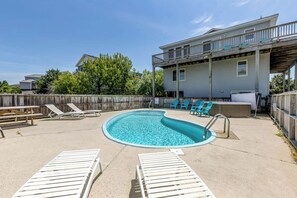 A backyard with a swimming pool, lounge chairs, and a wooden deck.