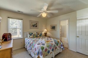 Une chambre à coucher avec un lit, un ventilateur de plafond, une fenêtre et une porte.