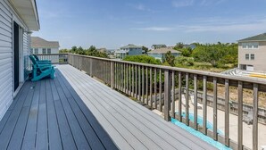 Una terraza de madera con piscina, rodeada de casas.