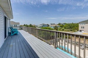 A wooden deck with a pool, surrounded by houses.