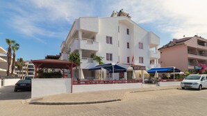 Un edificio blanco con balcones, una zona de estar al aire libre cubierta y un letrero que dice 'Hotel Apart'.