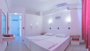 Un dormitorio con una cama grande, un armario, una mesita de noche y una ventana.