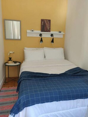 Cozy retreat with a bed, bedside table, and wall-mounted shelf.