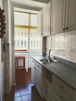 Kitchen with a window, stainless steel sink, and dark patterned tile flooring.