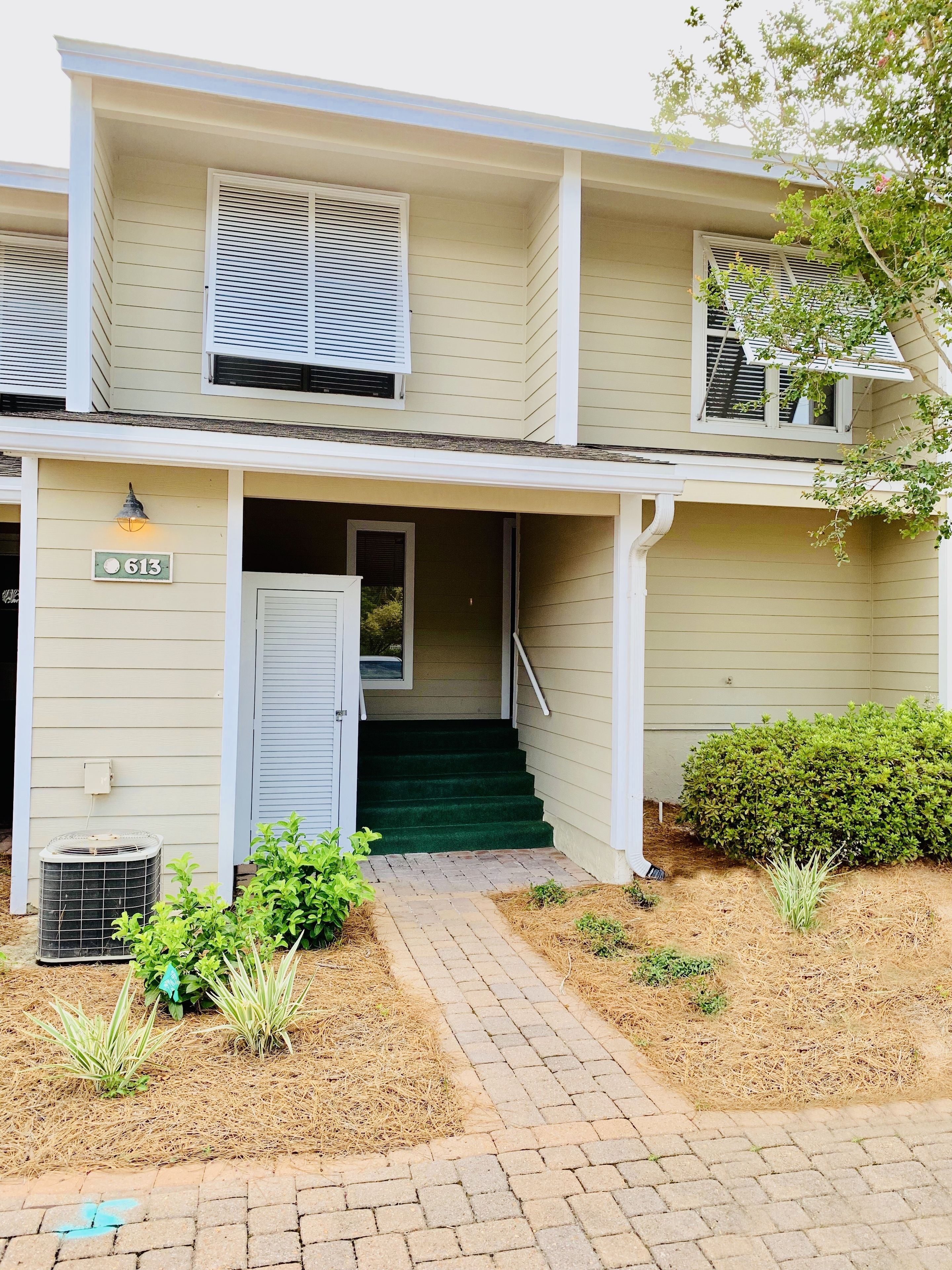 A two-story building with a front entrance, a small porch, and a staircase leading to the second floor.