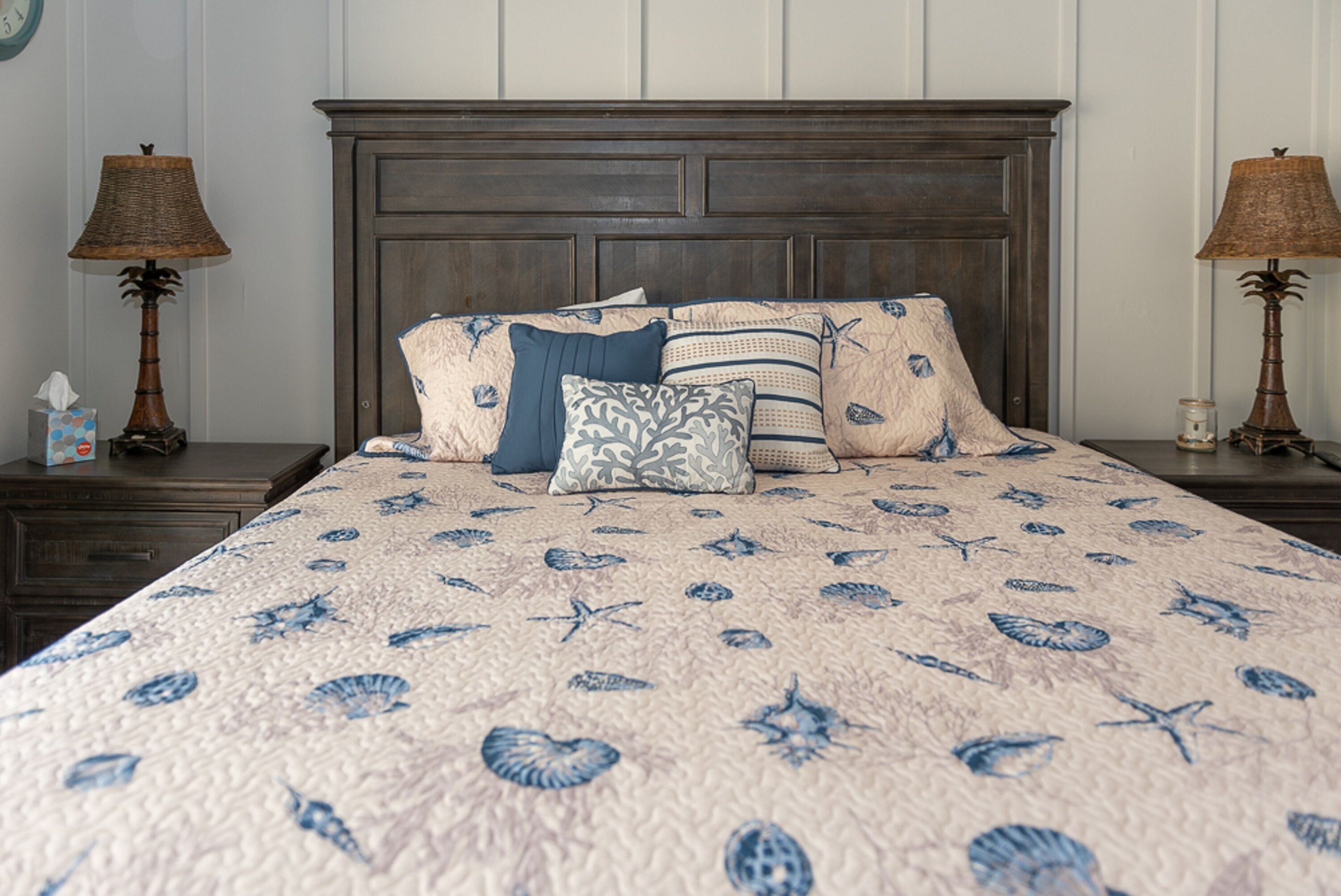 A bed with a floral pattern, a wooden headboard, and two bedside lamps.