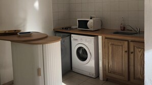 A compact kitchen with a washing machine, a microwave, and a sink. - Studio in historic district of Corte (Corte)