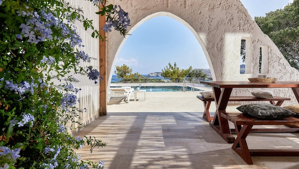 Un espace extérieur aménagé en terrasse, avec vue sur la mer, une piscine et un banc en bois.