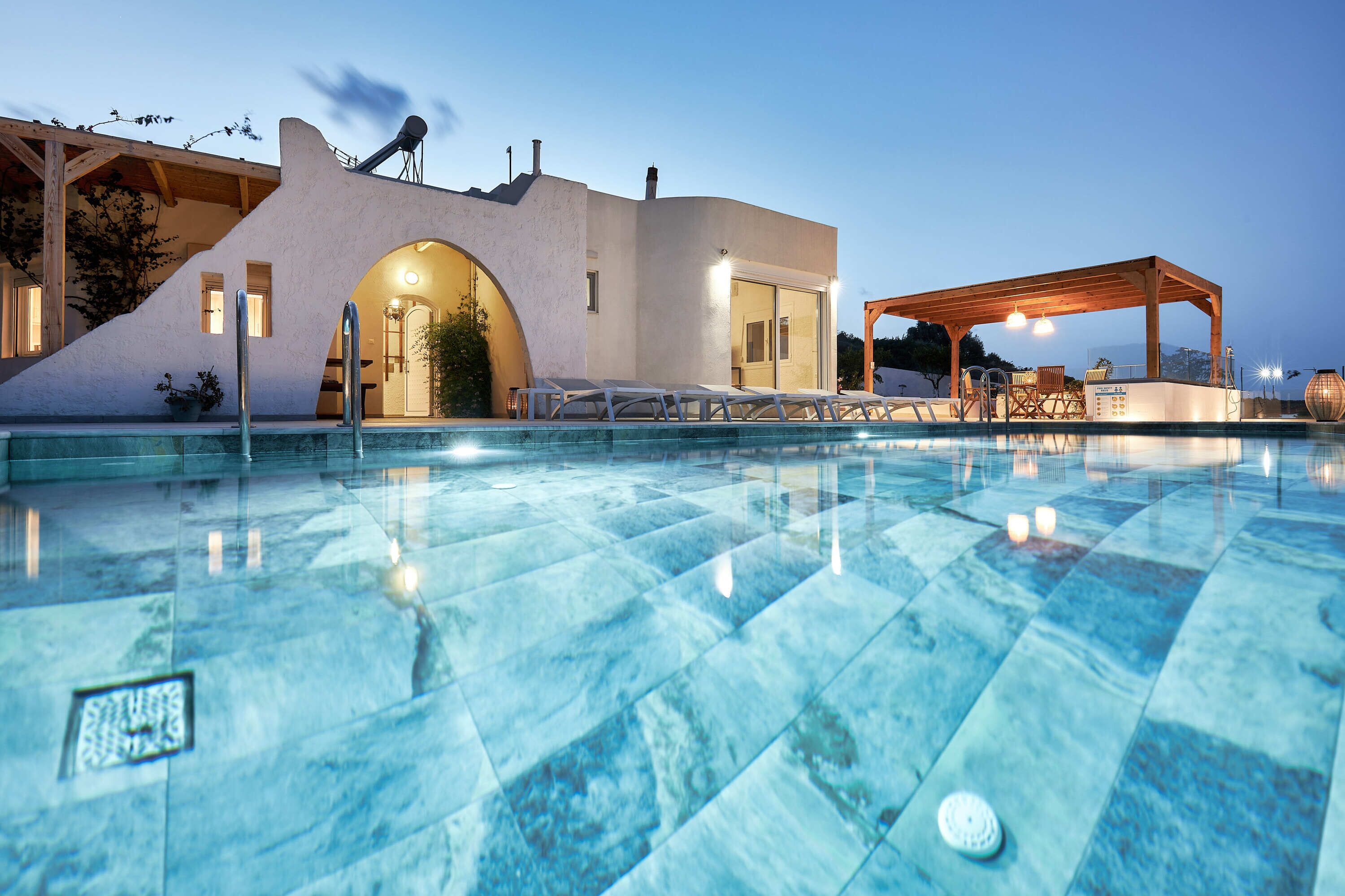 Un área de piscina moderna con una piscina cristalina, un espacio de descanso cubierto y un edificio de diseño arquitectónico único.