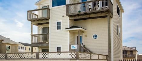A multi-story residential building with balconies, a gated entrance, and a visible sign indicating a rental property.