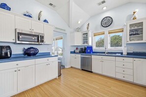 A modern kitchen with white cabinetry, a built-in microwave, and a coffee maker.