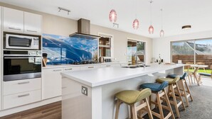 Une cuisine moderne avec des meubles blancs, un grand îlot central doté de tabourets et un éclairage suspendu.