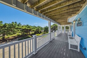 A covered wooden deck with white railings, benches, and a sign that reads 'Stillwater.'