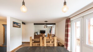 Una sala de estar moderna con un corralito de madera, un televisor y un comedor con mesa negra.