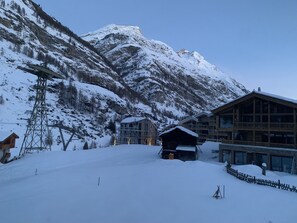 A snow-covered mountain with a wooden lodge and a tall utility tower.