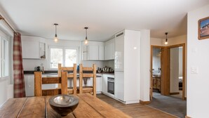 Una cocina moderna con armarios blancos, sillas de madera y una mesa de comedor de madera.