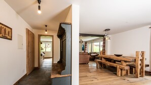 Un amplio espacio habitable con una mesa de madera y bancos, una escalera y vistas al exterior.