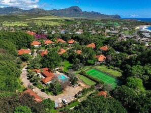 Vue aérienne d’un quartier résidentiel avec des maisons, un court de tennis et une piscine.