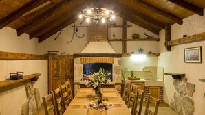 Une salle à manger rustique avec une table en bois, des chaises et un lustre.