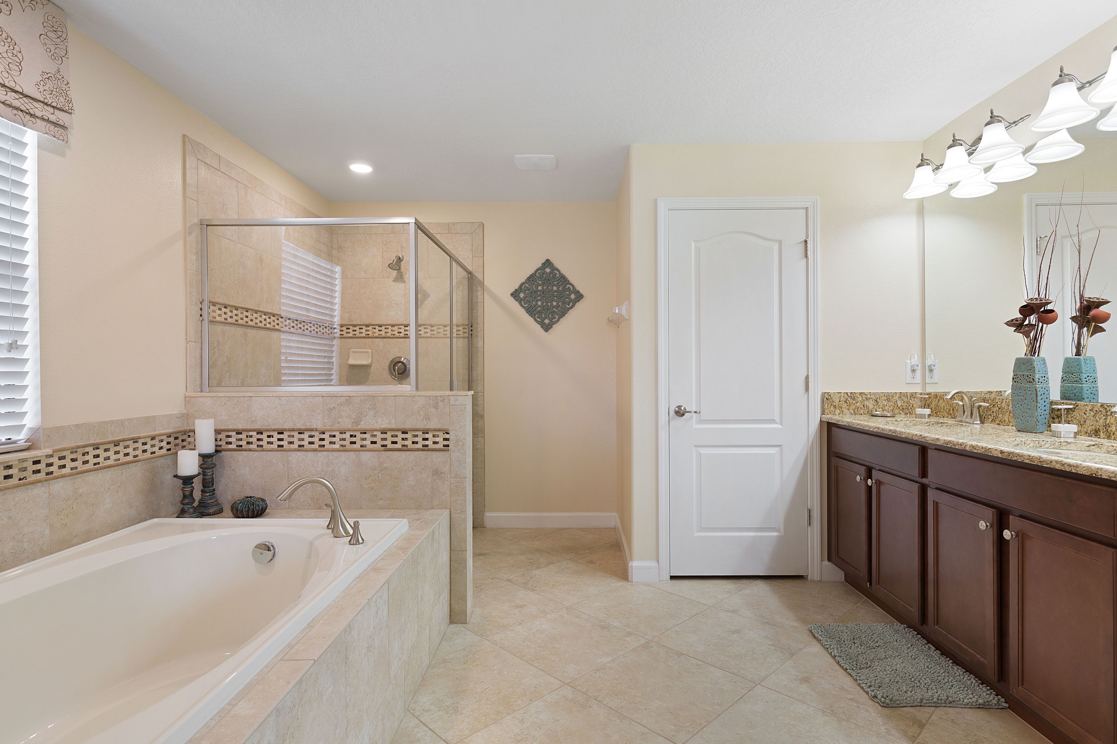 A bathroom with a bathtub, a shower, a vanity with a mirror, and a door.